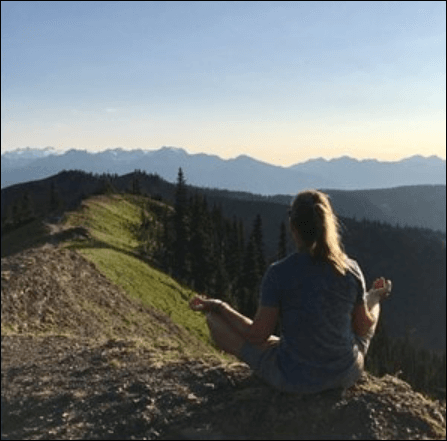 Woman on top of mountain meditating